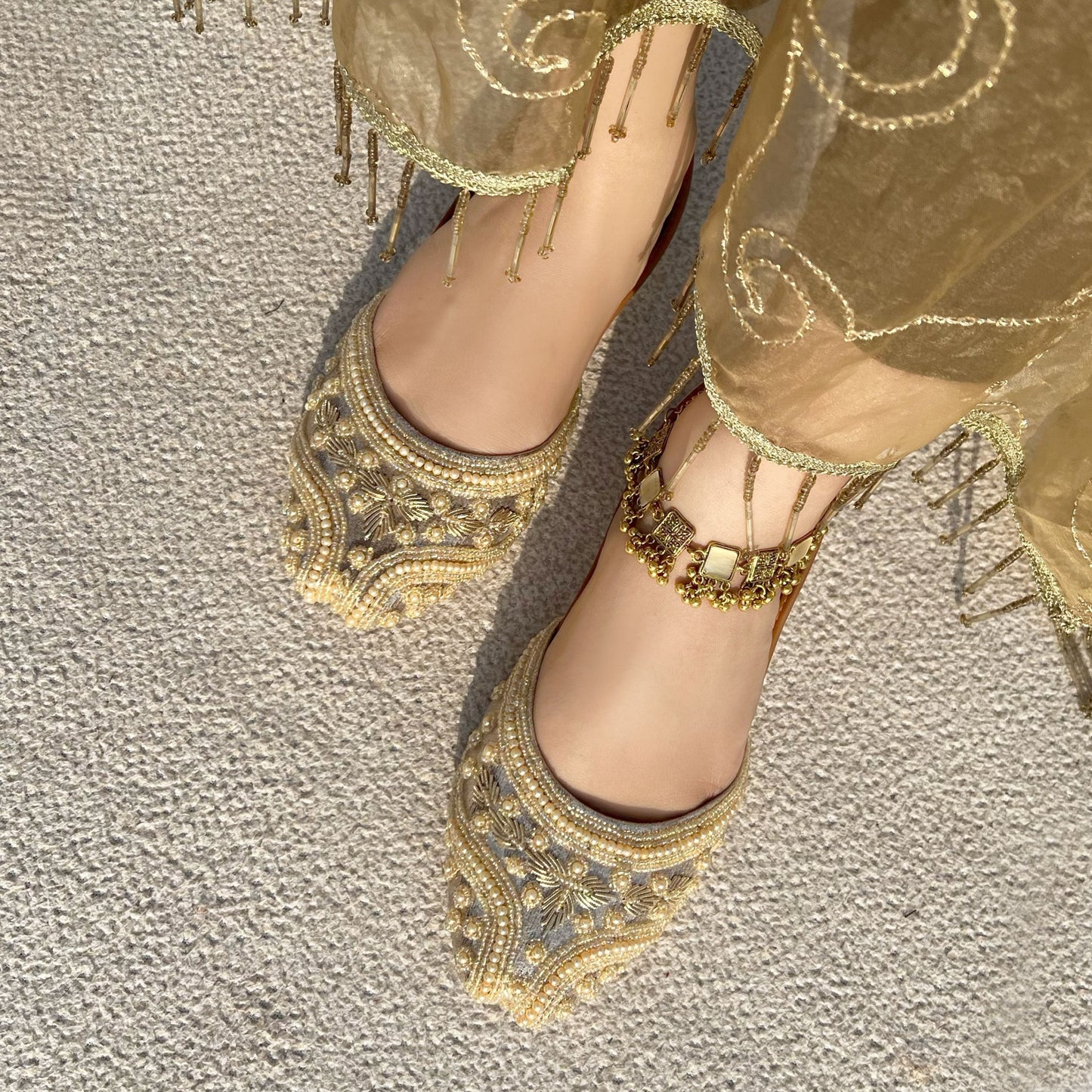 Gold embroidered shoes on a textured surface
