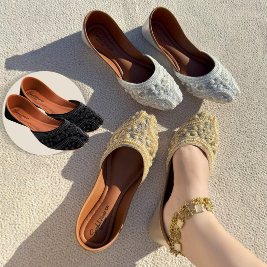 Pair of gold embroidered flats on a textured surface with other pairs in the background.